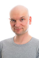 young man with bald head  is smiling in to the cam